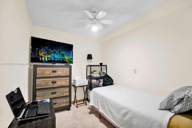 bedroom featuring ceiling fan, light tile patterned floors, and a textured ceiling