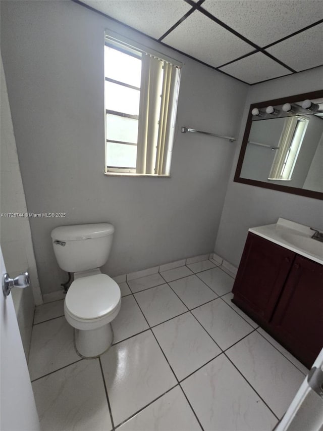 bathroom featuring toilet, vanity, a paneled ceiling, and tile patterned flooring