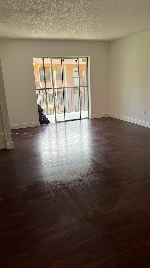 empty room featuring a textured ceiling and dark hardwood / wood-style flooring