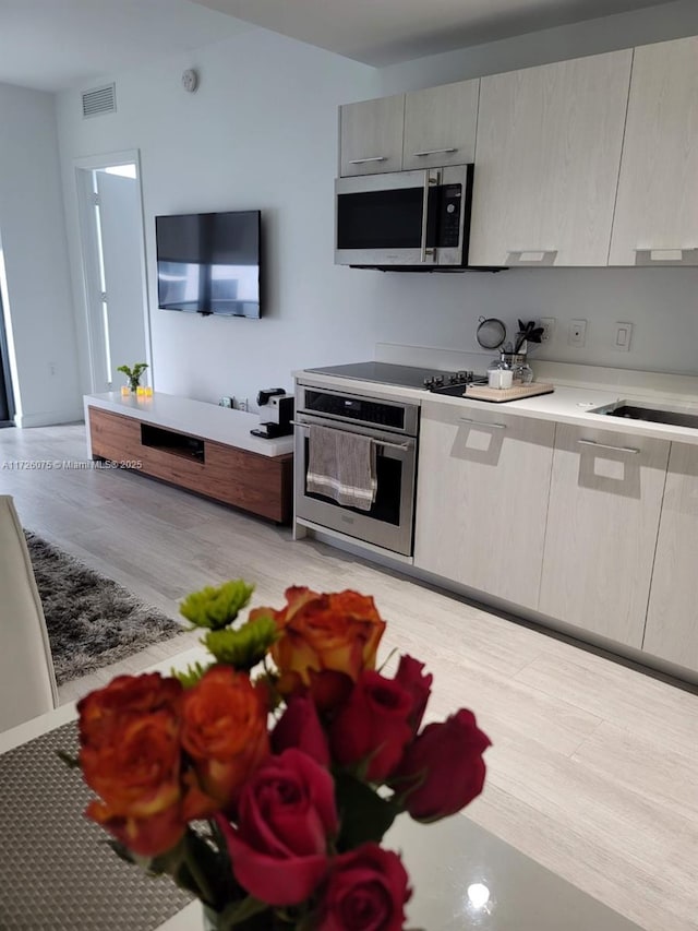 kitchen featuring appliances with stainless steel finishes, light hardwood / wood-style flooring, and sink