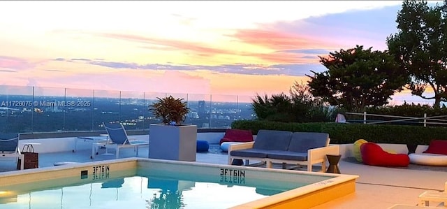 pool at dusk featuring an outdoor hangout area and a patio area