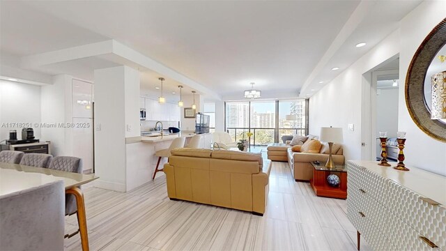 living room featuring floor to ceiling windows, a notable chandelier, and sink