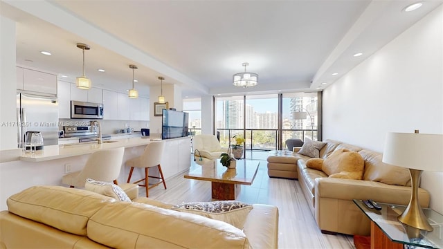 living room featuring floor to ceiling windows, light wood-type flooring, and a chandelier