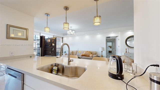 kitchen featuring kitchen peninsula, dishwasher, hanging light fixtures, white cabinets, and sink