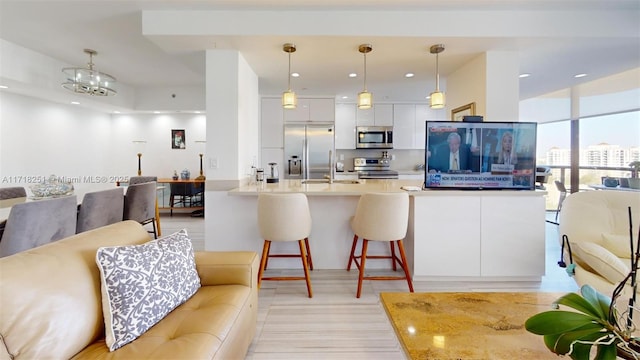 kitchen featuring stainless steel appliances, a kitchen breakfast bar, pendant lighting, and white cabinetry