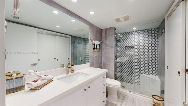 bathroom featuring toilet, vanity, and a shower with shower door