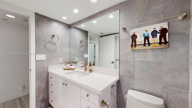 bathroom with toilet, tile walls, and vanity