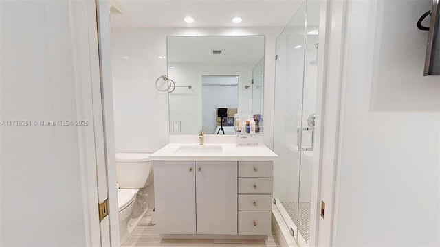 bathroom featuring a shower with shower door, vanity, and toilet