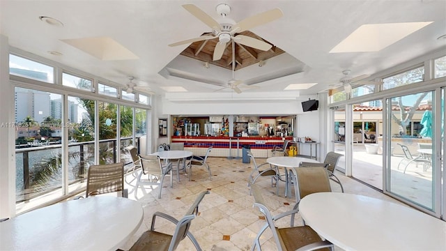 sunroom with a raised ceiling, ceiling fan, and a skylight