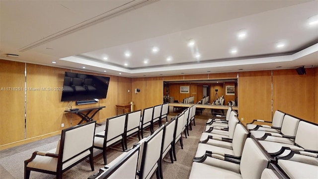 cinema featuring a raised ceiling, wood walls, and light colored carpet