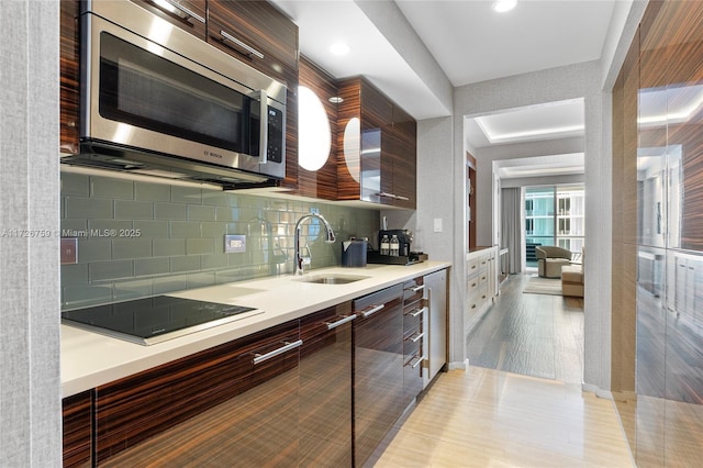 kitchen with black electric stovetop, light tile patterned floors, dark brown cabinetry, sink, and tasteful backsplash