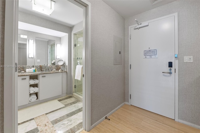 bathroom with electric panel, hardwood / wood-style floors, vanity, and a shower with shower door