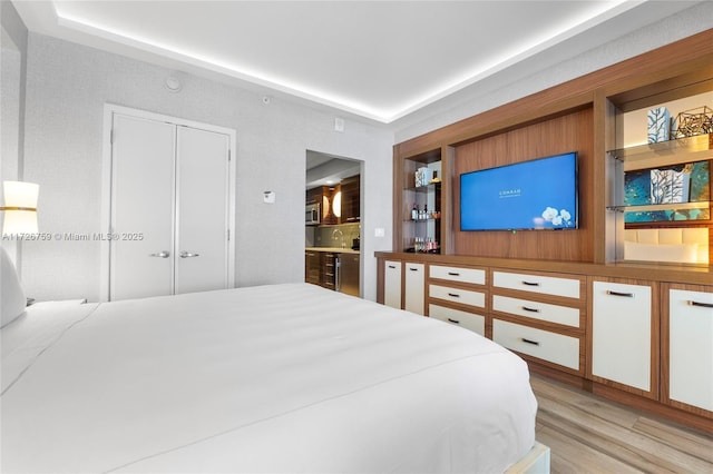 bedroom featuring a closet, connected bathroom, and light hardwood / wood-style floors