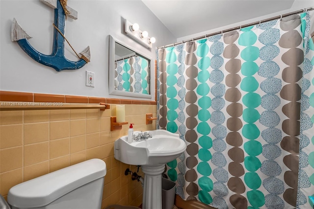 bathroom featuring toilet, a shower with shower curtain, and tile walls