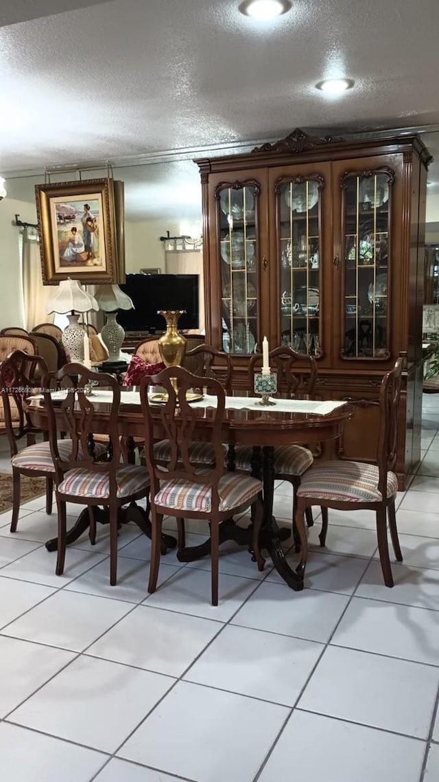 tiled dining space with a textured ceiling and crown molding