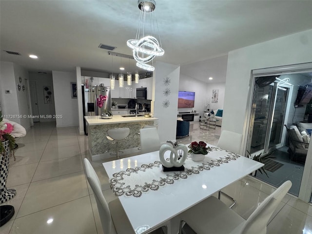 dining space featuring light tile patterned flooring, sink, and a notable chandelier