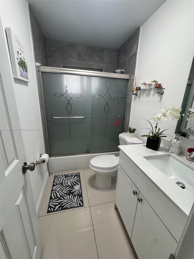 full bathroom featuring vanity, bath / shower combo with glass door, tile patterned floors, and toilet