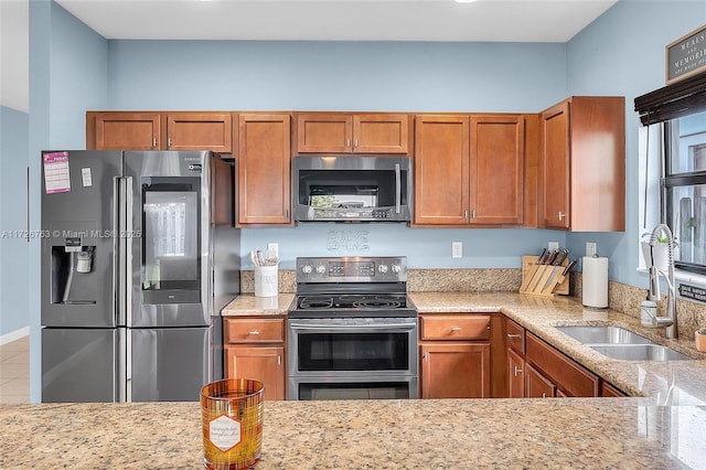 kitchen featuring tile patterned flooring, appliances with stainless steel finishes, sink, and light stone counters