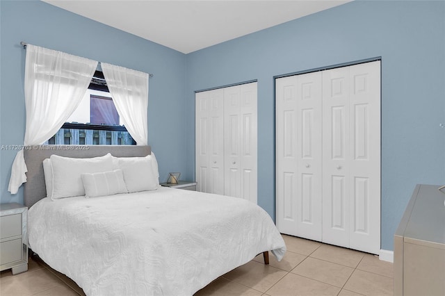 bedroom featuring light tile patterned floors and multiple closets