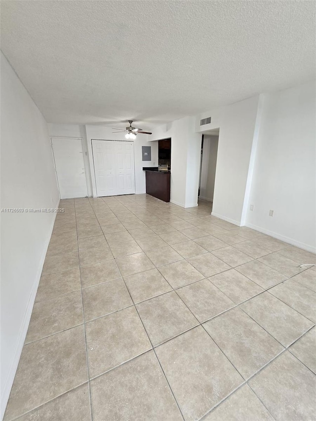 spare room featuring a textured ceiling, ceiling fan, and light tile patterned floors