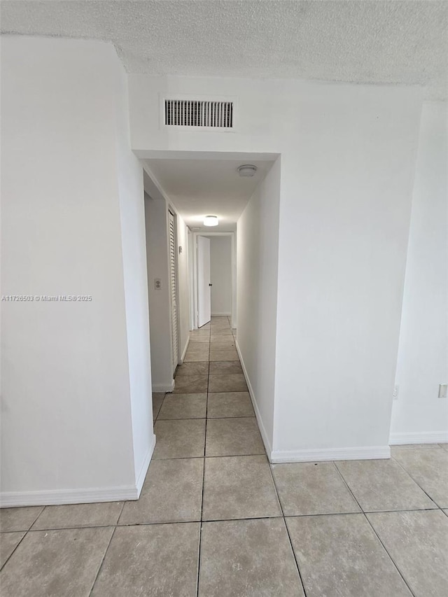 hall with light tile patterned flooring and a textured ceiling