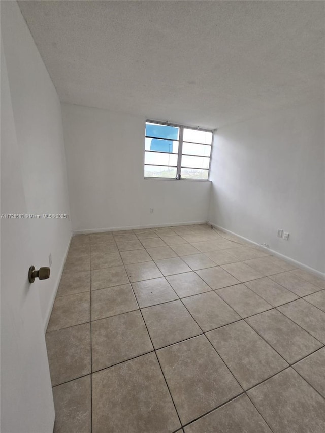 tiled empty room featuring a textured ceiling