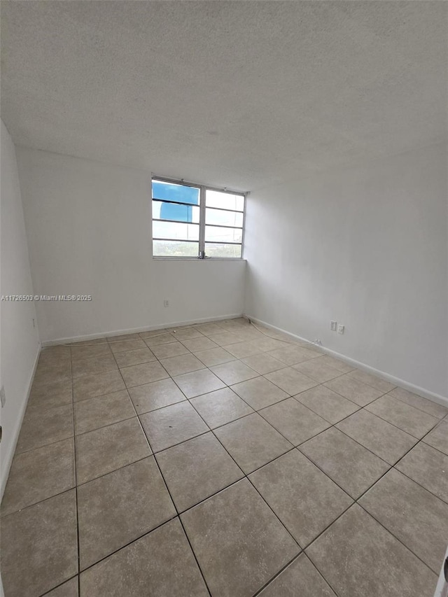 tiled empty room with a textured ceiling