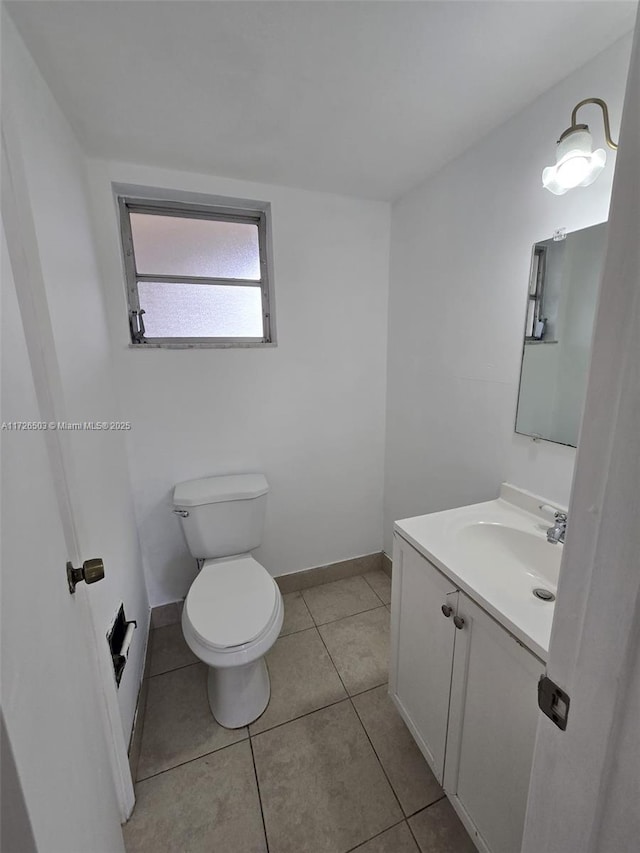 bathroom with toilet, vanity, and tile patterned flooring