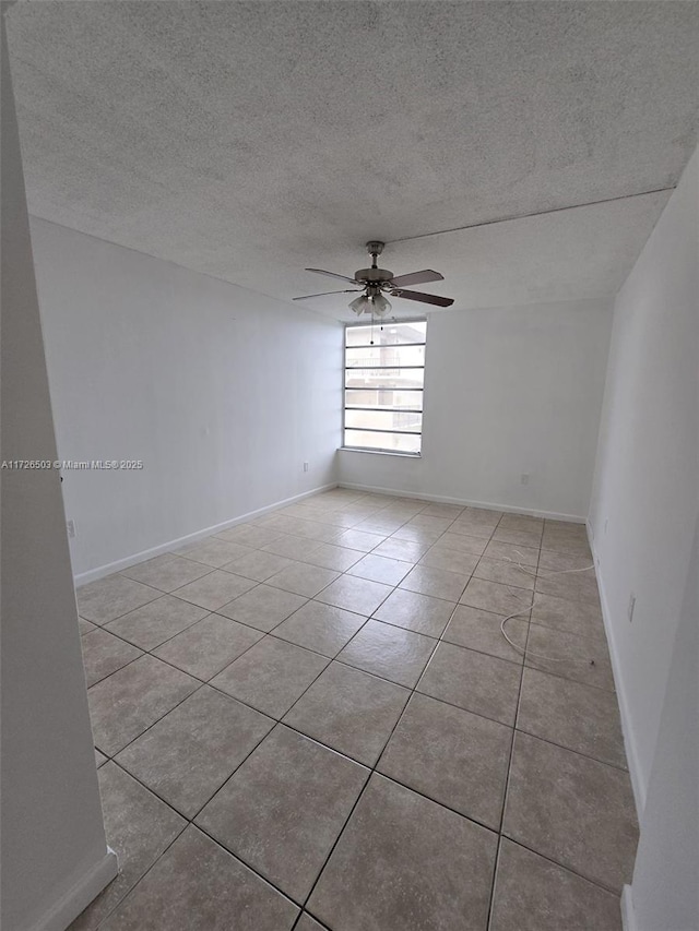 empty room with a textured ceiling, ceiling fan, and light tile patterned floors