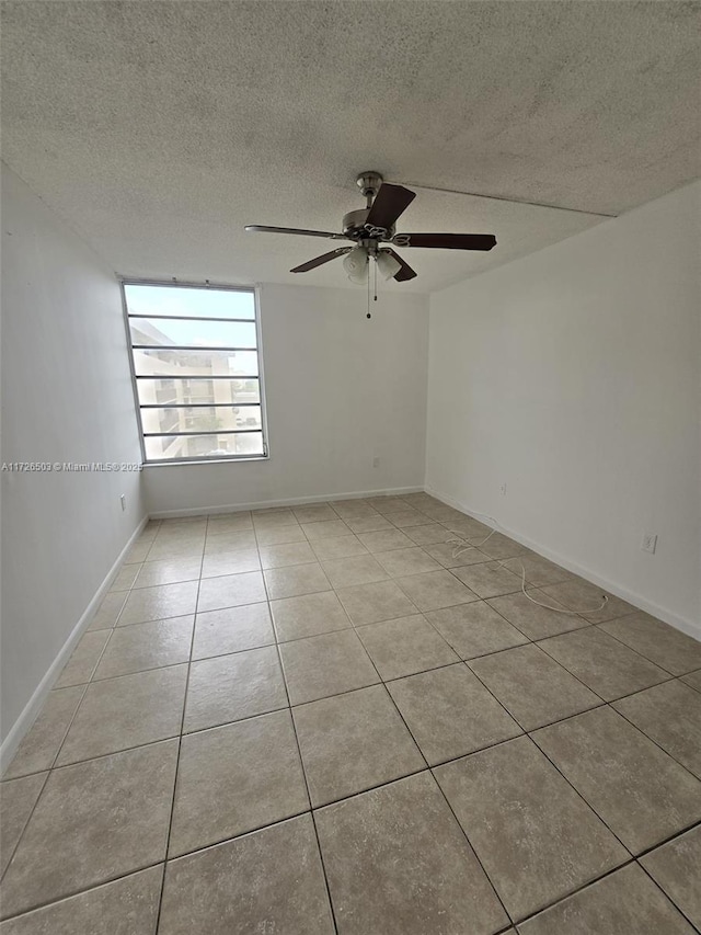 unfurnished room featuring a textured ceiling, ceiling fan, and light tile patterned floors