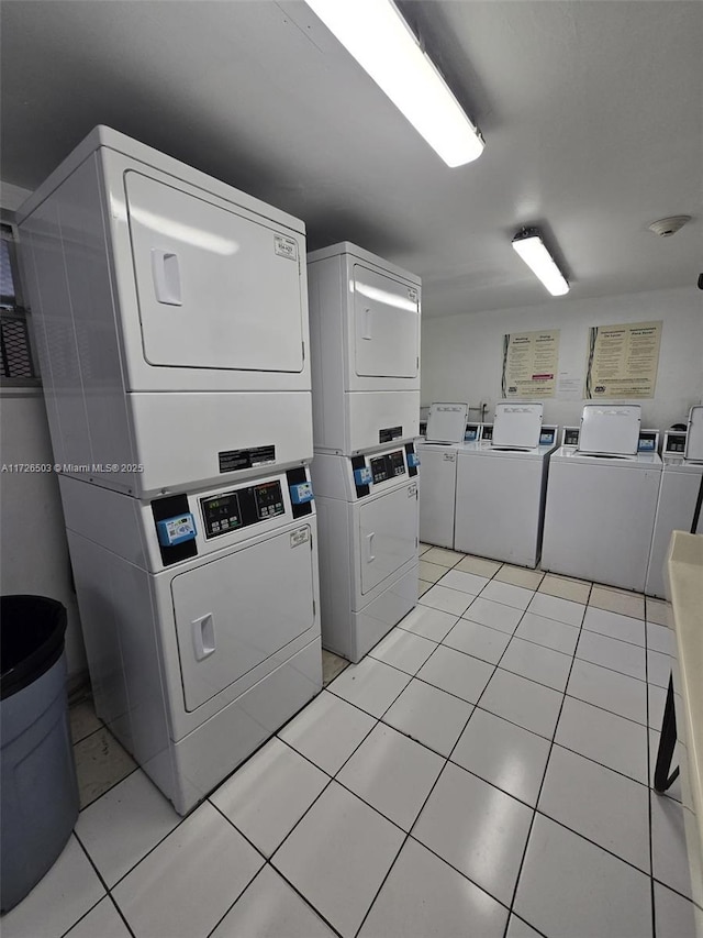 clothes washing area featuring stacked washing maching and dryer and light tile patterned flooring