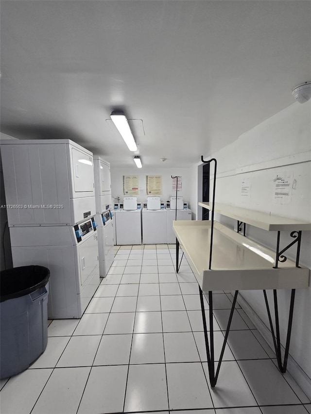 laundry area with stacked washer / drying machine and light tile patterned floors