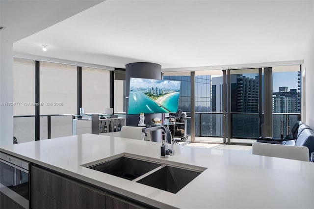 kitchen with stainless steel microwave, a sink, light countertops, open floor plan, and modern cabinets