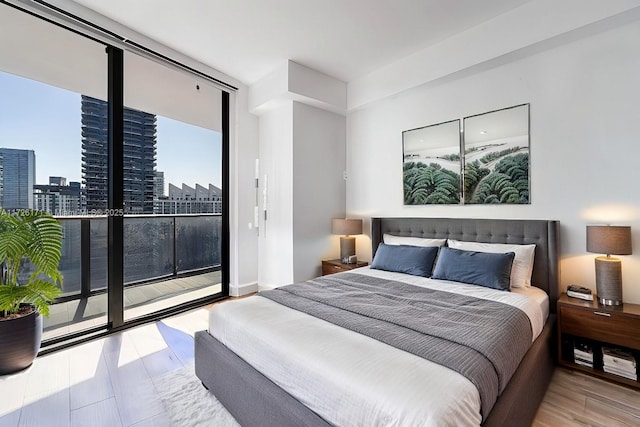 bedroom with a view of city, wood finished floors, and access to exterior