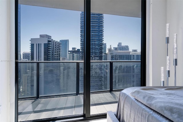 bedroom featuring floor to ceiling windows, wood finished floors, and a city view