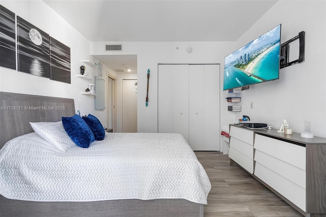 bedroom with a closet, visible vents, and wood finished floors