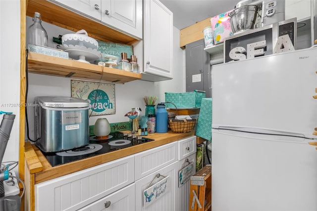 kitchen featuring white cabinets, white refrigerator, and black electric cooktop