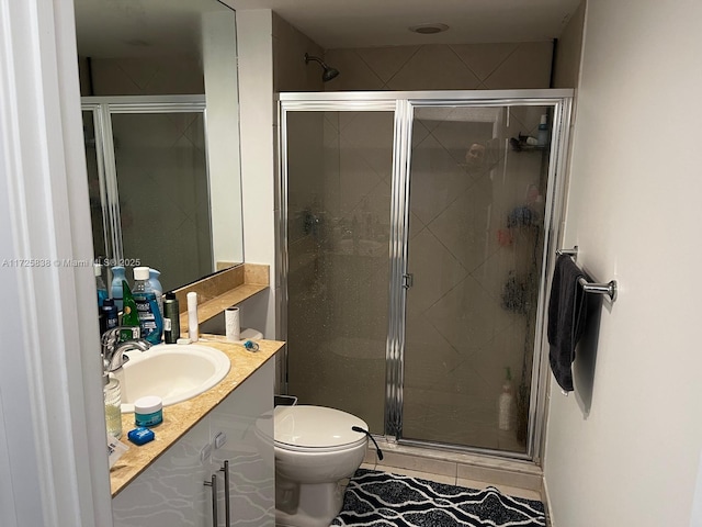 bathroom with toilet, a shower with shower door, tile patterned floors, and vanity