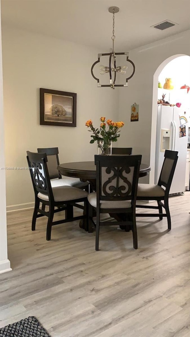 dining space featuring a notable chandelier and light wood-type flooring