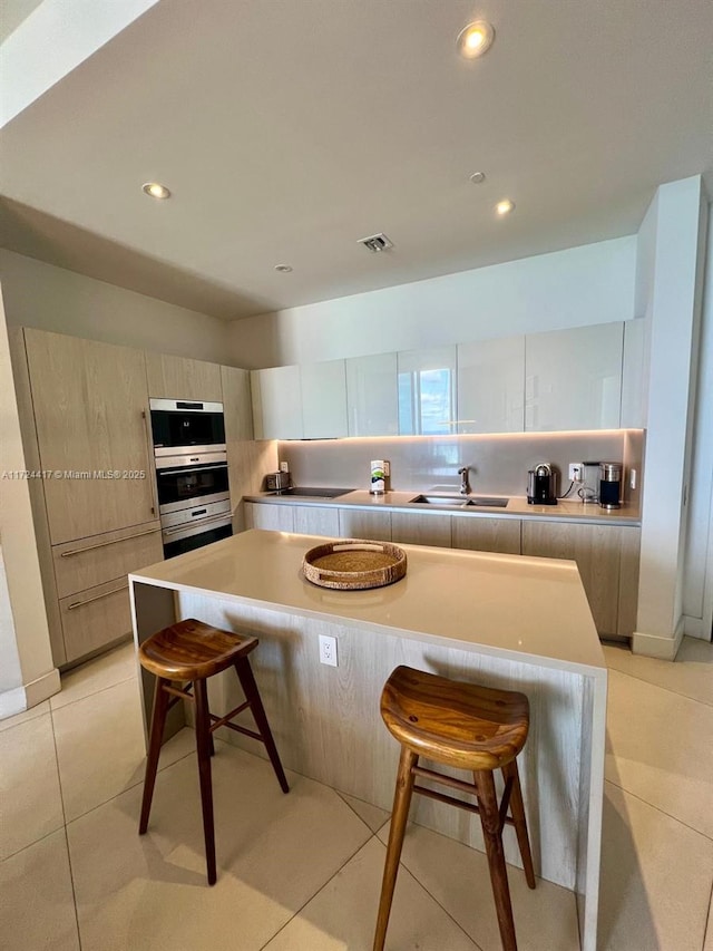 kitchen featuring sink, a breakfast bar, a center island, and light tile patterned flooring