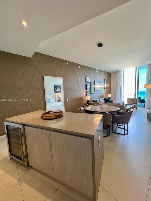 kitchen featuring decorative light fixtures, a spacious island, washer / dryer, beverage cooler, and light brown cabinets