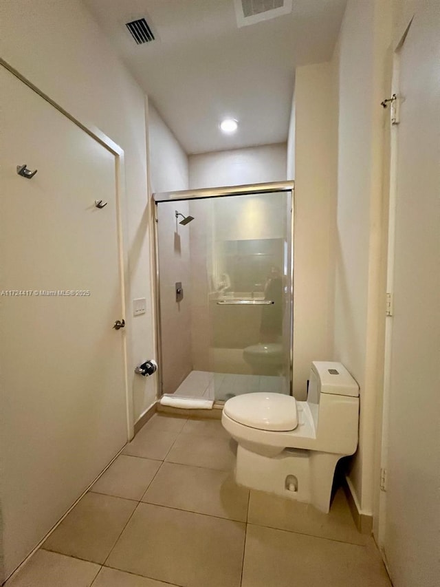 bathroom with toilet, tile patterned floors, and a shower with shower door