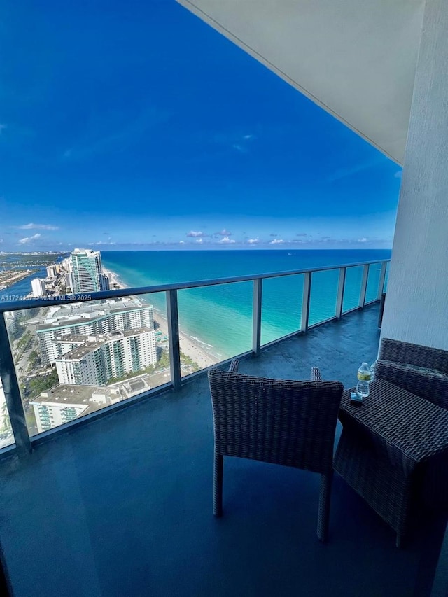 balcony featuring a view of the beach and a water view