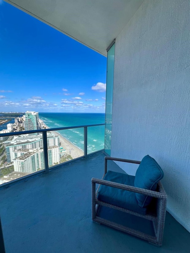 balcony with a water view and a view of the beach