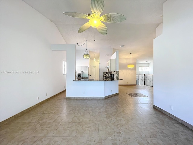 kitchen with kitchen peninsula, ceiling fan, stainless steel fridge, white cabinetry, and decorative light fixtures