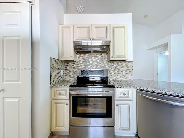 kitchen featuring appliances with stainless steel finishes, light stone countertops, kitchen peninsula, decorative backsplash, and cream cabinets