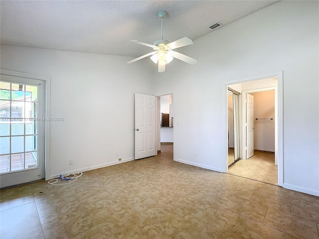 unfurnished bedroom featuring a walk in closet, multiple windows, high vaulted ceiling, and ceiling fan