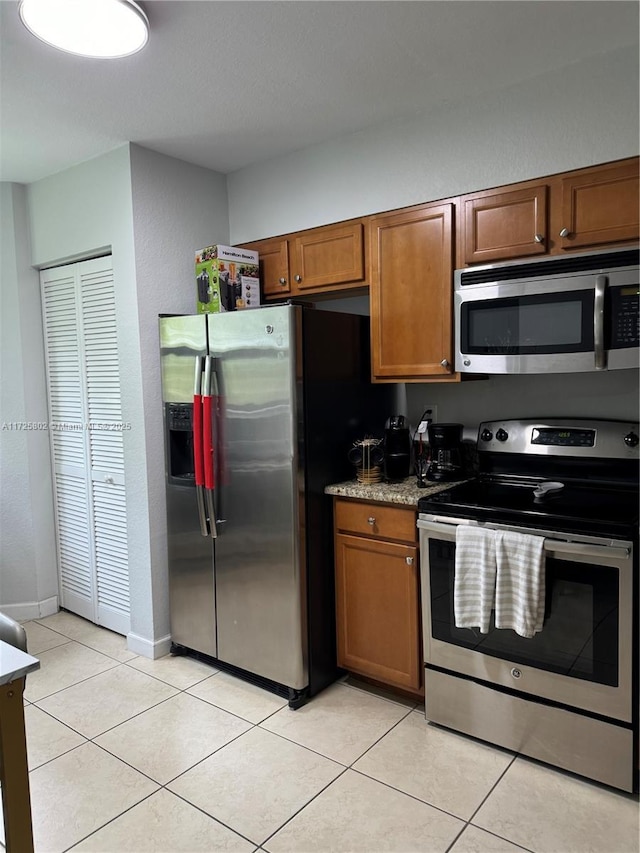 kitchen featuring light stone counters, stainless steel appliances, and light tile patterned flooring