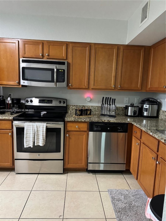 kitchen with light tile patterned flooring, appliances with stainless steel finishes, and stone countertops