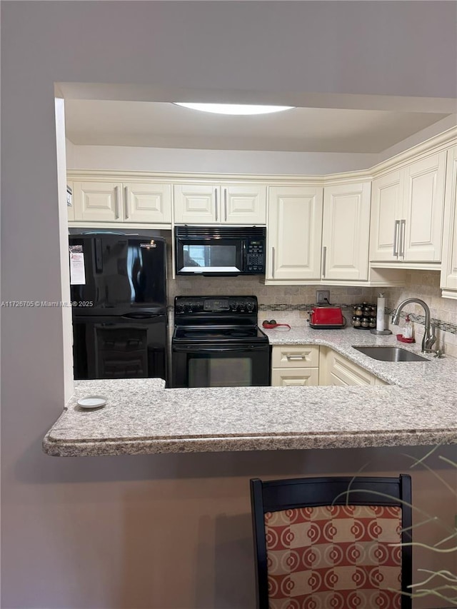 kitchen featuring decorative backsplash, sink, light stone counters, and black appliances